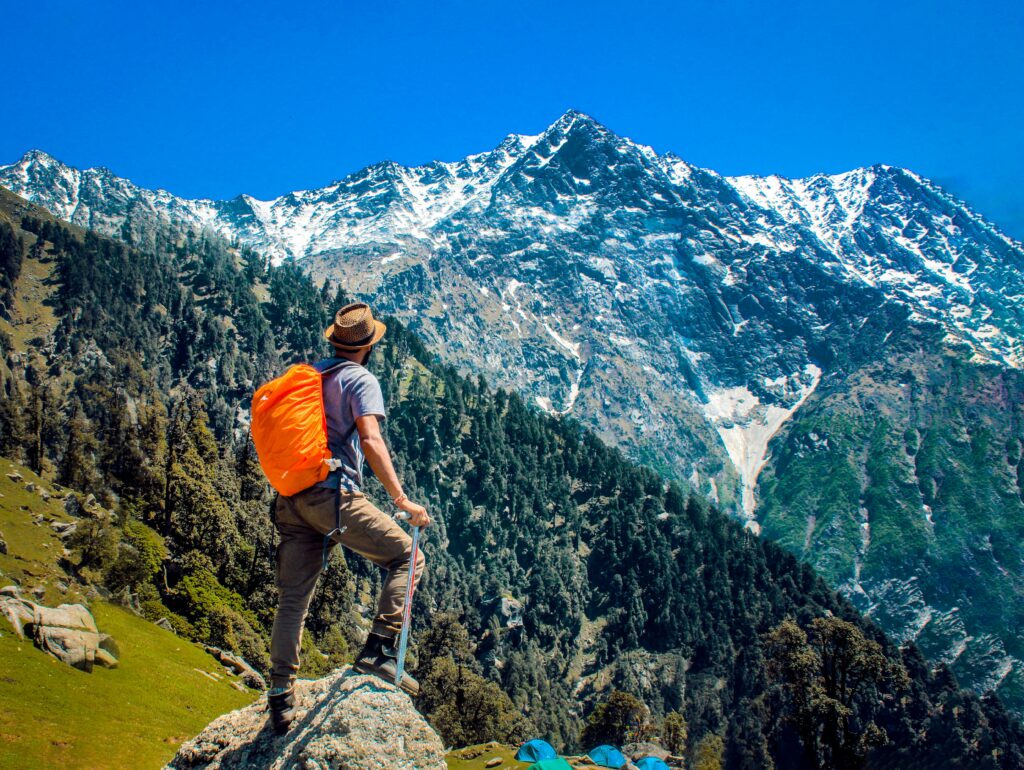 Man exploring breathtaking mountain scenery with snow-capped peaks under a clear blue sky.