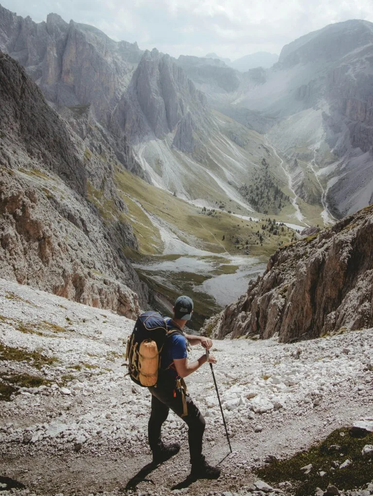 A solo hiker explores a rocky mountain valley with scenic views.